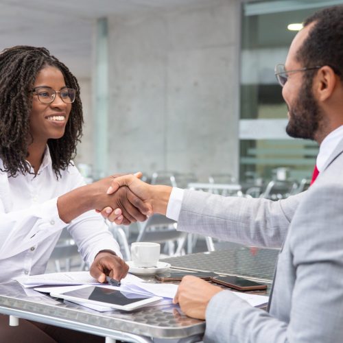Smiling businesswoman shaking hands with partner. Cheerful businesspeople reaching agreement. Handshake concept